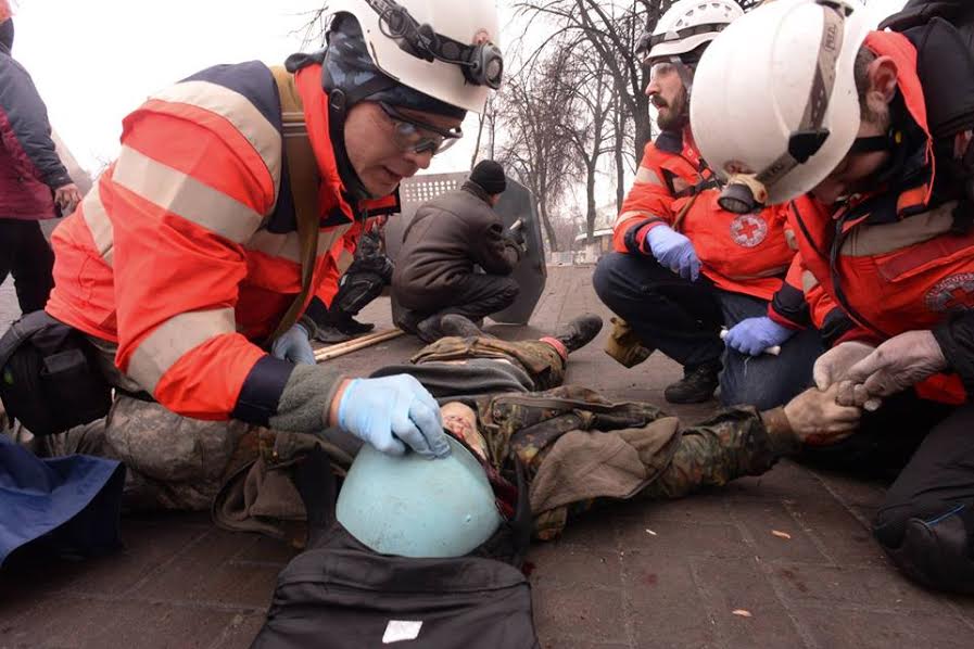 February 20, 2014. Instytutska Street, Kyiv, Ukraine. Roman (second to the right) and volunteer doctors are examining the body of Ustym Golodnyuk. Roman will be shot in a few seconds. Photograph: Mstislav Chernov.