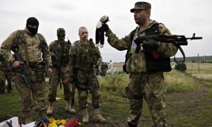 A pro-Russia fighter holds up a toy found among the debris at the crash site of MH17. (Image: Dmitry Lovetsky/AP) 