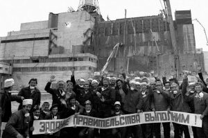 Nuclear accident mitigation workers near the damaged Chornobyl reactor, 1986. The sign says: "We Will Fulfill The Task Given by The Party!" (Image: belaruspartisan.org)