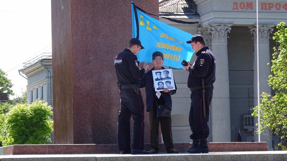 Russian policemen detain Crimean Tatar activist Server Karametov, who stood with the national flag and the photos of his deported parents at the central square of occupied Simferopol. He was not even allowed to lay flowers on the monument to the 1944 victims. Photo: Anton Naumlyuk