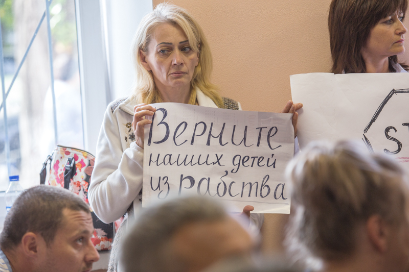 "Return our children from slavery." Mother of an imprisoned victim of the drug trafficking scheme holds a placard during a court hearing of the criminal suspects in the case. Photo: tyzhden.ua