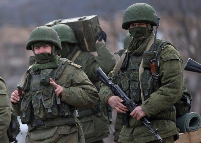 A soldier of the Russian annexation force flashes a victory sign while marching near a Ukrainian army base in Perevalne, Crimea. March 2014