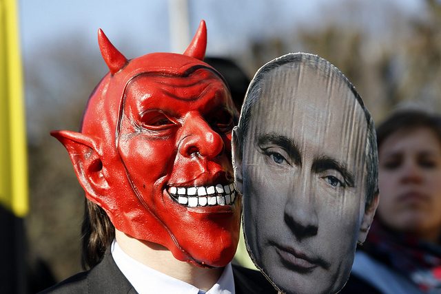 An activist wears a devil's mask which he covers with a picture of Vladimir Putin as part of a protest against the Russian President outside the congress center of the Hanover trade fair on April 7, 2013 in Hanover, western Germany. Putin arrived for the official opening of the industrial trade fair with German Chancellor Angela Merkel (not in pic). Activists and critics said Putin should be held to account for a recent crackdown on non-governmental organisations promoting democratic reforms in Russia. Image: AFP PHOTO / ODD ANDERSEN
