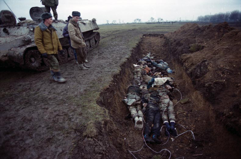 Russian soldiers next to a mass grave with Chechen militia and civilians during the Second Russian-Chechen War. Note the ropes used to drag corpses behind the army vehicles from the place of killing to the grave (Image: Natalia Medvedeva, wikipedia.org)