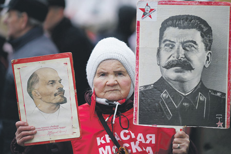 An old Russian woman holding portraits of Lenin and Stalin at a demonstration in Moscow (Image: Reuters)