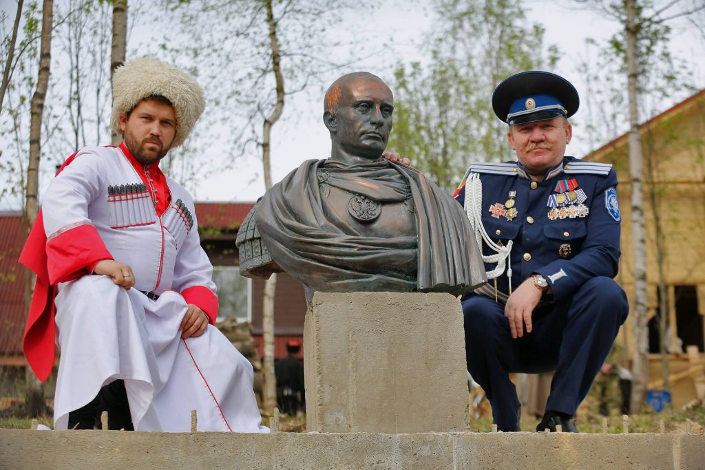 Russian neo-Cossack paramilitaries pose by a Putin monument in St. Petersburg, Russia