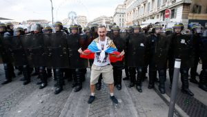 A Russian football/soccer fan posing with a national flag in front of French police protecting the order at the 2016 UEFA European Cup in France, June 2016 (Image: social media)