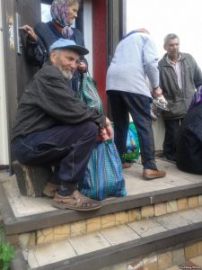 Elderly locals queuing at a soup kitchen