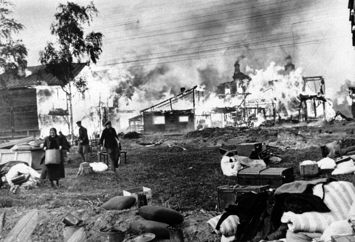 Russian men and women rescue their humble belongings from their burning homes, set on fire by the Soviets, part of a scorched-earth policy, in a Leningrad suburb on October 21, 1941. (Image: AP)