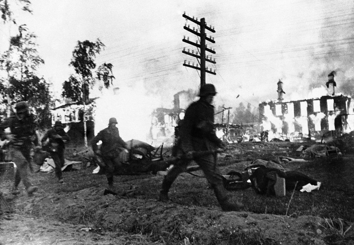 German troops make a hasty advance through a blazing Leningrad suburb, in Russia on November 24, 1941. (Image: AP)
