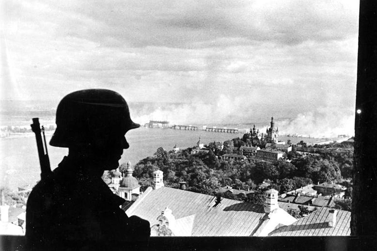 With a burning bridge across the Dnipro River in the background, a German sentry keeps watch in the recently-captured city of Kyiv, Ukraine in 1941. (Image: Deutsches Bundesarchiv/German Federal Archive)