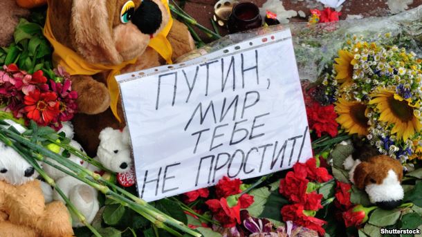 Flowers left near the Dutch embassy in Kyiv, Ukraine for victims of Malaysia Airlines MH17. The note says in Russian: "Putin, the world will not forgive you."
