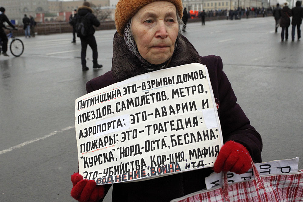 A woman at the 2015 Boris Nemtsov Memory March on 1 March 2015 in Moscow, Russia. Her sign says: "Putinism it is explosions of apartment buildings, airplanes, metro stations, airports; it is incidents and fires; it is tragedies of 'Kursk,' 'Nord-Ost,' Beslan; it is murders, corruption, mafia, war..." (Image: kykyryzo.ru)