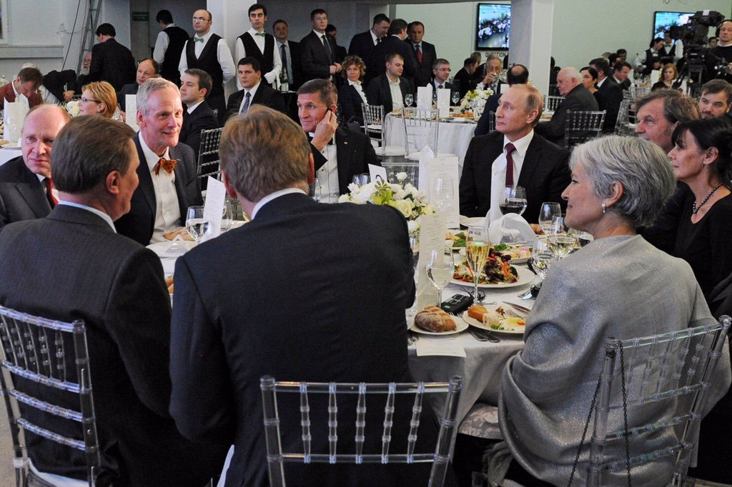 Donald Trump's former national security advisor, former Director of US Defense Intelligence Agency, retired Lieutenant General Mike Flynn at a conference and gala dinner celebrating the 10th anniversary of Russia’s propaganda arm, media channel “RT” (formerly “Russia Today”) seated at the head table at the gala, with Vladimir Putin, his then-chief of staff, Sergei Ivanov and press spokesman Dmitry Peskov, among other Russian officials. Also seated at the same table is 2016 Green Party candidate for US president Dr. Jill Stein. December 10, 2015 in Moscow. (Image: video capture)