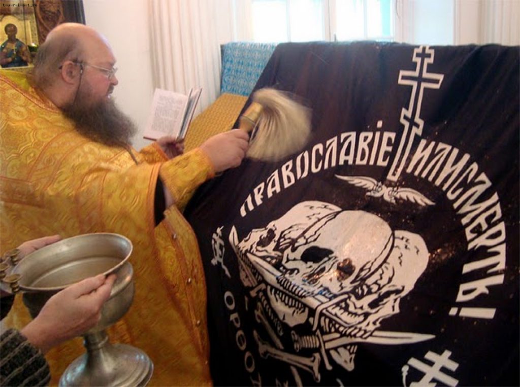 Russian Orthodox priest blesses a flag with a sign "The Orthodox Church or Death" (Image: politros.com)