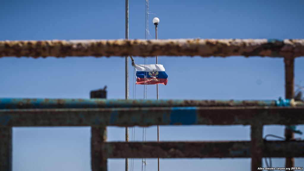 A Russian state flag flying in Moscow-annexed Crimea next to its neglected and rusting infrastructure (Image: Alina Smutko, krymr.org/RFE/RL)