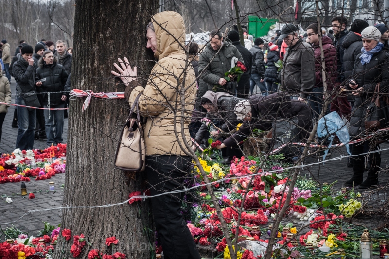 A woman stands near a tree where a Euromaidan protester was killed days before. Photo: Andriy Lomakin. 23 February 2014 ~