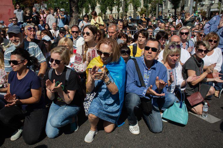 Kyivans attending the Defenders’ March kneel while the relatives carrying photos of their family members killed in the Donbas pass by. Photo: hromadske,ua ~