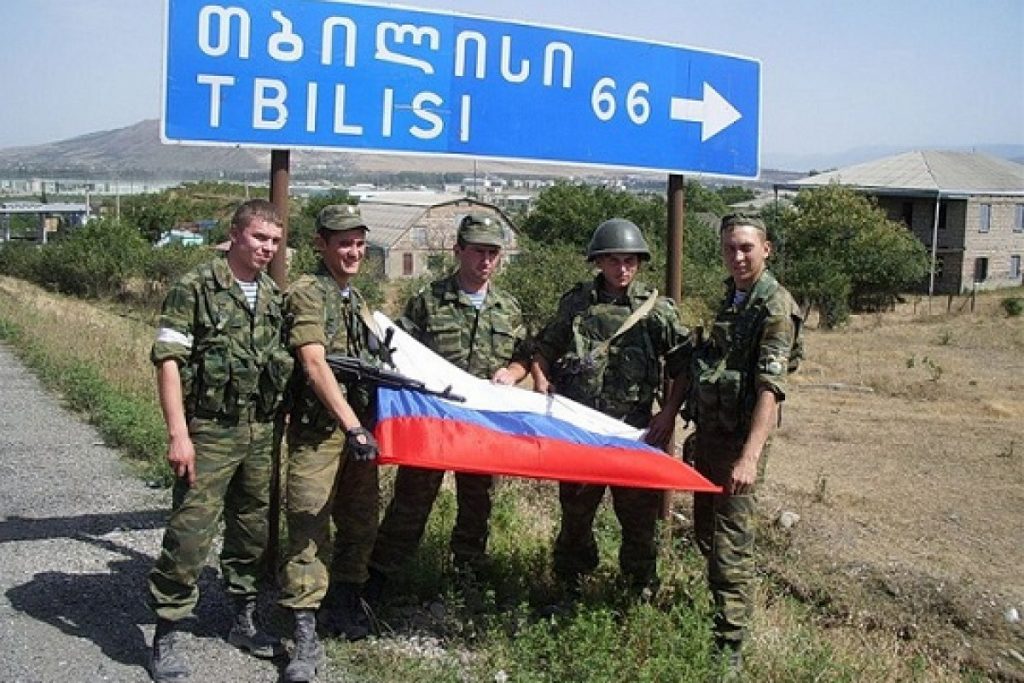 Russian soldiers invading Georgia taking photographs by the road sign showing 66 kilometers to the country's capital Tbilisi. August 2008. Photo: Social media