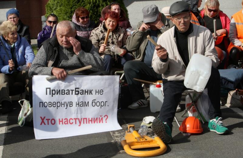 Workers of the Nikopol Ferrum Alloys Plant rally in front of the PrivatBank headquarters in Dnipro on September 19. “PrivatBank didn’t pay its debt to us. Who’s next?” the sign says. Source: Kyiv post ~
