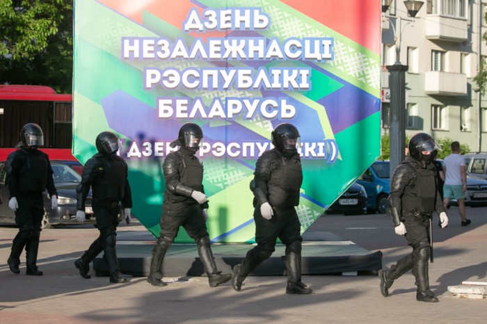 Belarusian riot police in front of the poster congratulating with Belarusian independence day. Source: voices from Belarus ~