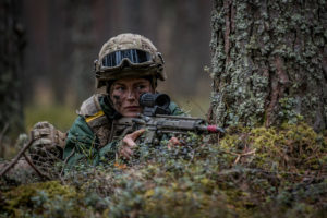 A female Danish soldier hiding in the woods during exercise Crystal Arrow 2023 in Latvia.