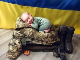 A baby sleeping on Ukrainian soldier’s equipment.