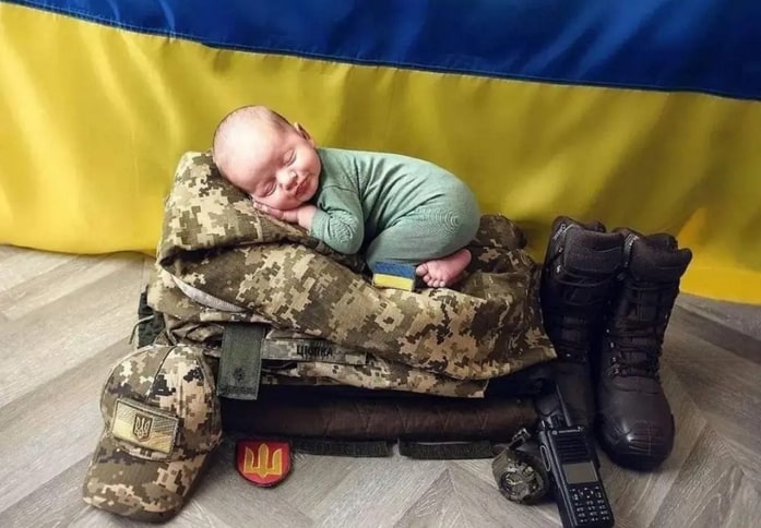 A baby sleeping on Ukrainian soldier's equipment.