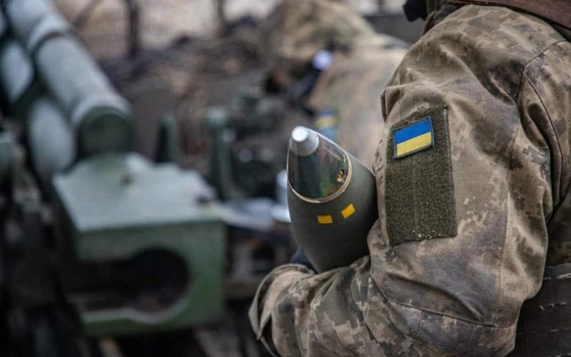 Ukrainian soldiers carry an artillery shell.