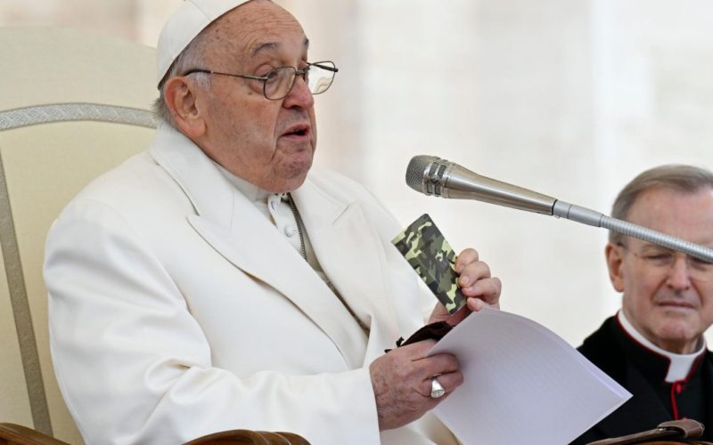 Pope Francis holding the rosary and the camouflaged New Testament book of a young Ukrainian soldier killed in the war during his general audience