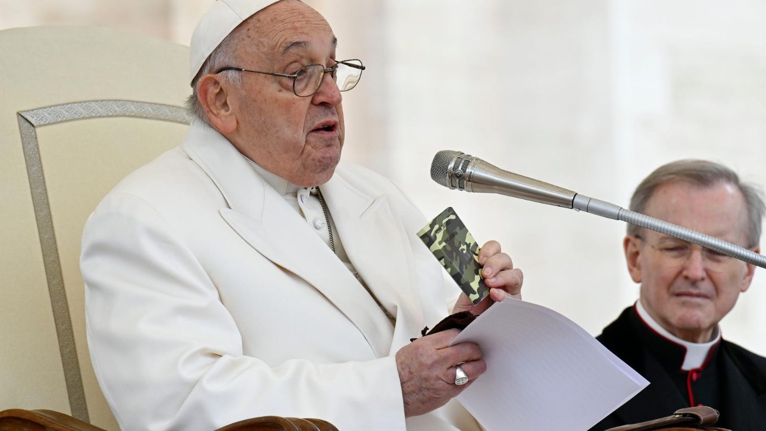 Pope Francis holding the rosary and the camouflaged New Testament book of a young Ukrainian soldier killed in the war during his general audience
