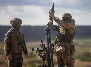 A Ukrainian soldier loads a mortar shell under the supervision of a French army instructor (L) during a military training with French servicemen, in a military training compound at an undisclosed location in Poland