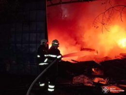 Ukrainian rescuer is extinguishing fire after Russian attack.