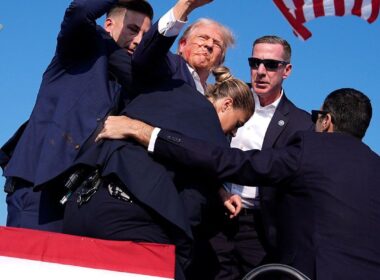 Former President Donald Trump, with blood on his face, raises his fist to the crowd as he is surrounded by Secret Service agents at his campaign rally in Butler, Pennsylvania.