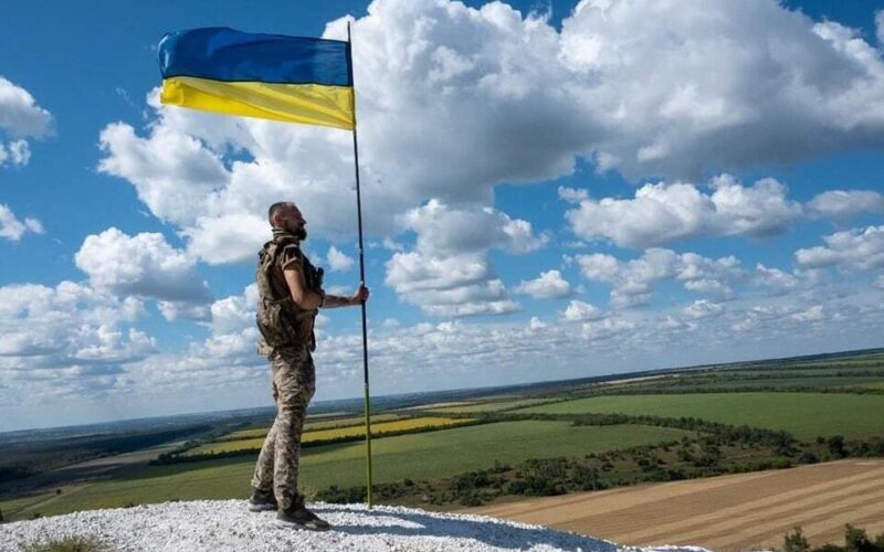 Ukrainian soldier near a Ukrainian flag