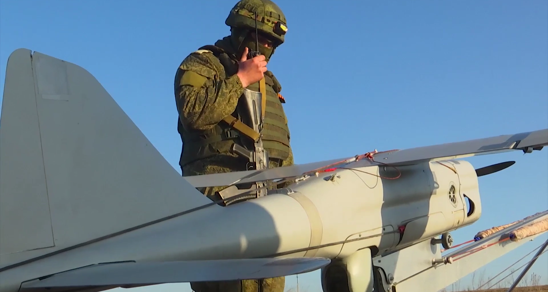 A Russian soldier standing next to an Orlan-10 uncrewed aerial reconnaissance vehicle. Photo via Wikimedia.