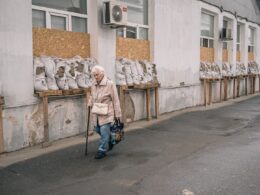 wp russian drones targeting kherson civilians ongoing human safari woman walks past windows covered wooden planks sandbags outside hospital