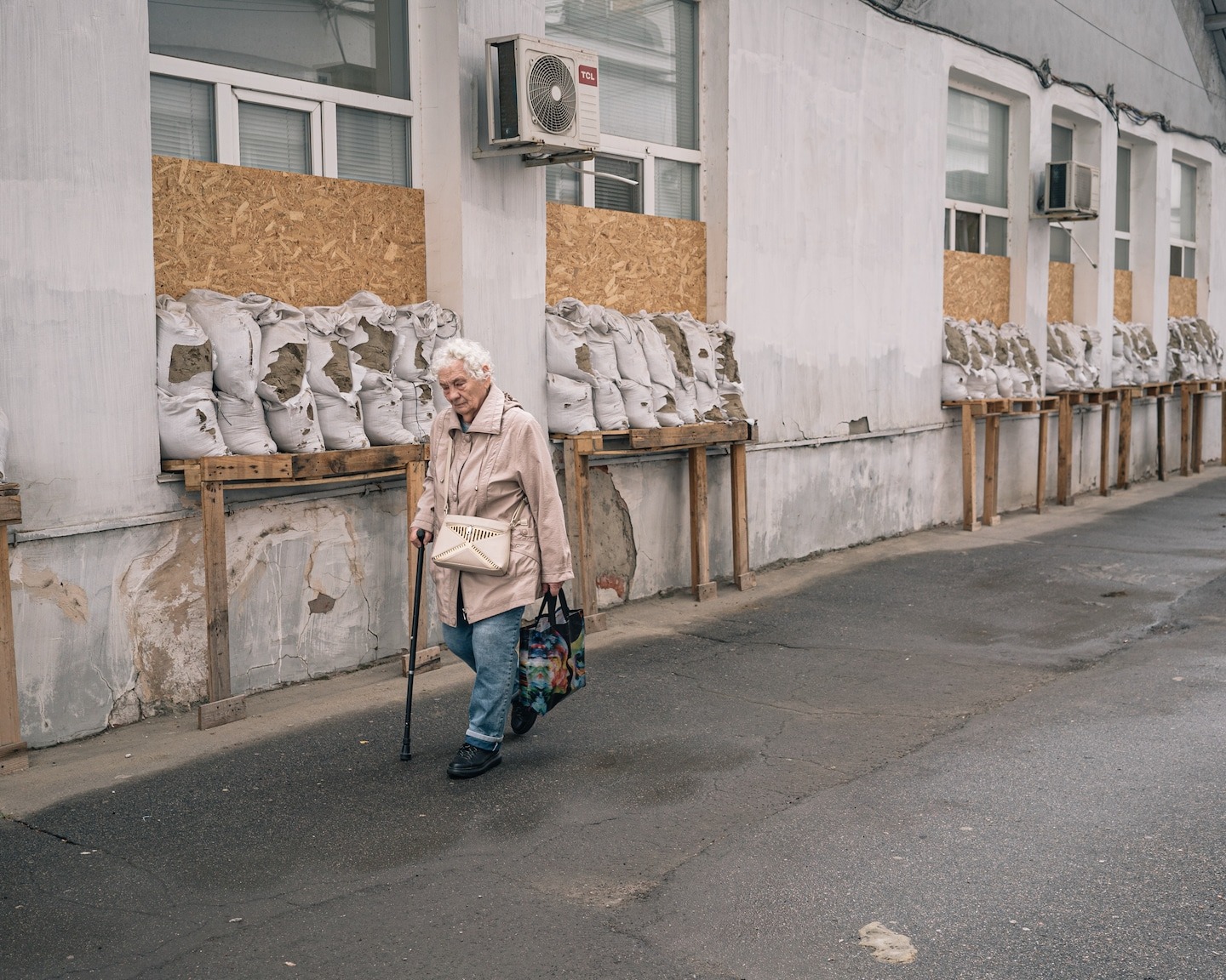 wp russian drones targeting kherson civilians ongoing human safari woman walks past windows covered wooden planks sandbags outside hospital