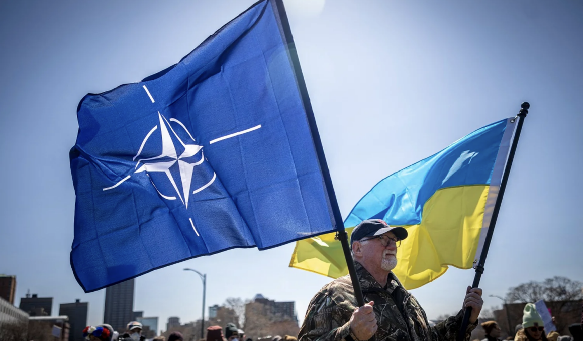 A man at the Hands Off protest against Trump in Minnesota is holding flags of Ukraine and NATO.