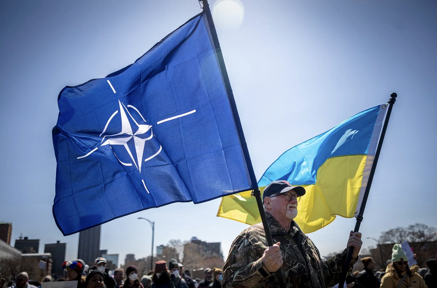 A man at the Hands Off protest against Trump in Minnesota is holding flags of Ukraine and NATO.