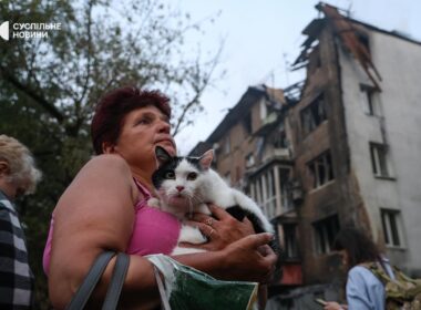 russia strikes kyiv 10 hours—two women killed including 22-year-old metro police officer woman holds cat front residential building damaged russian shahed drone 2025 people watch burn after attack suspilne news