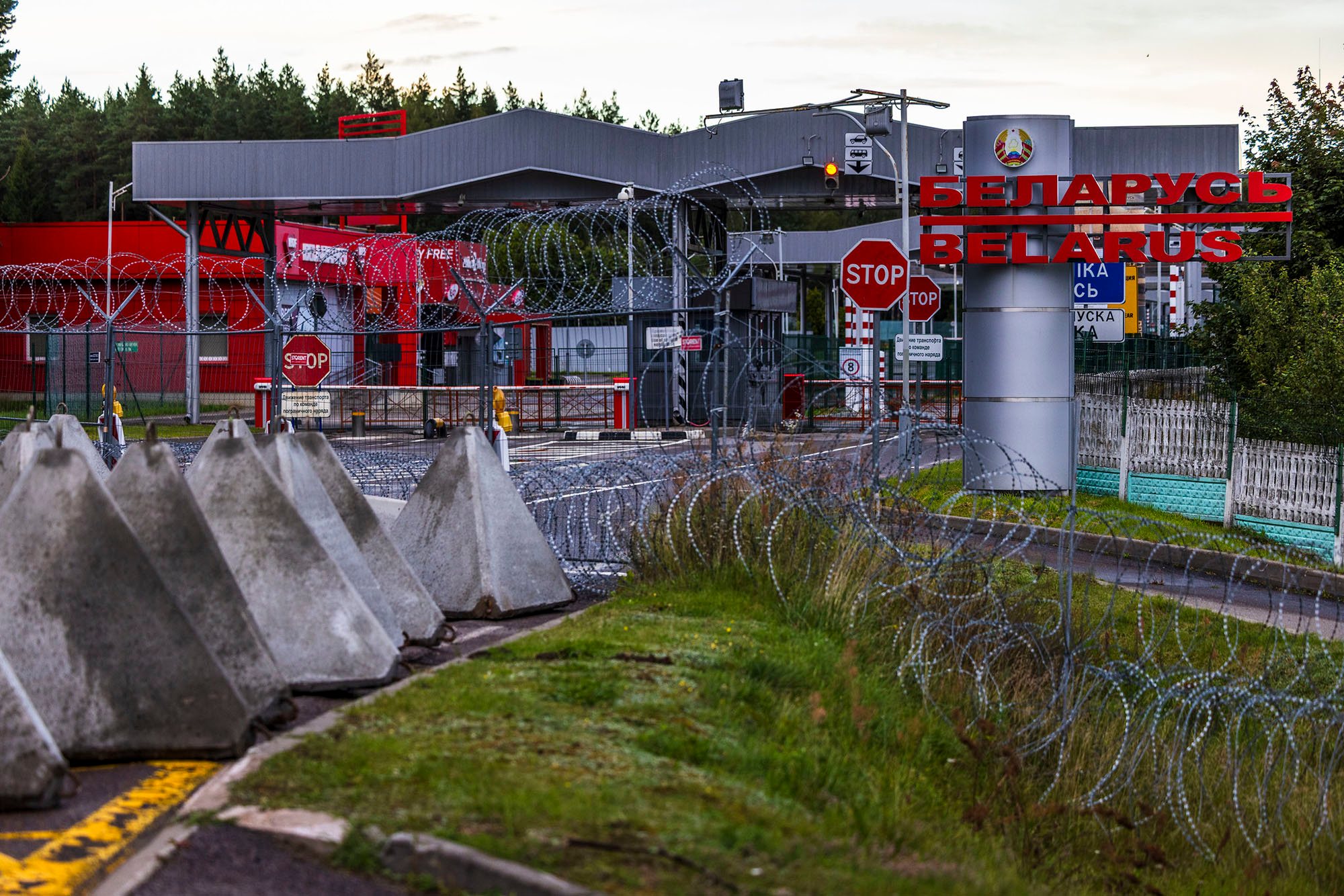 Concrete anti-tank barriers known as "dragon's teeth" are positioned at a Lithuania-Belarus border crossing point. The triangular obstacles are part of Lithuania's defensive measures to strengthen border security and restrict vehicle movement as part of the planned Baltic Defense Line.