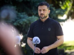 Ukrainian President Volodymyr Zelenskyy speaking at microphones during an outdoor press briefing.