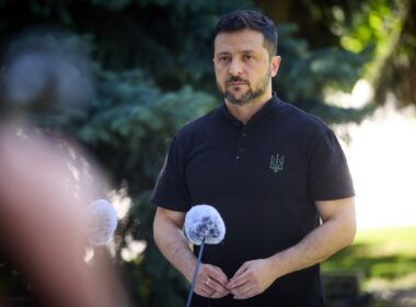 Ukrainian President Volodymyr Zelenskyy speaking at microphones during an outdoor press briefing.