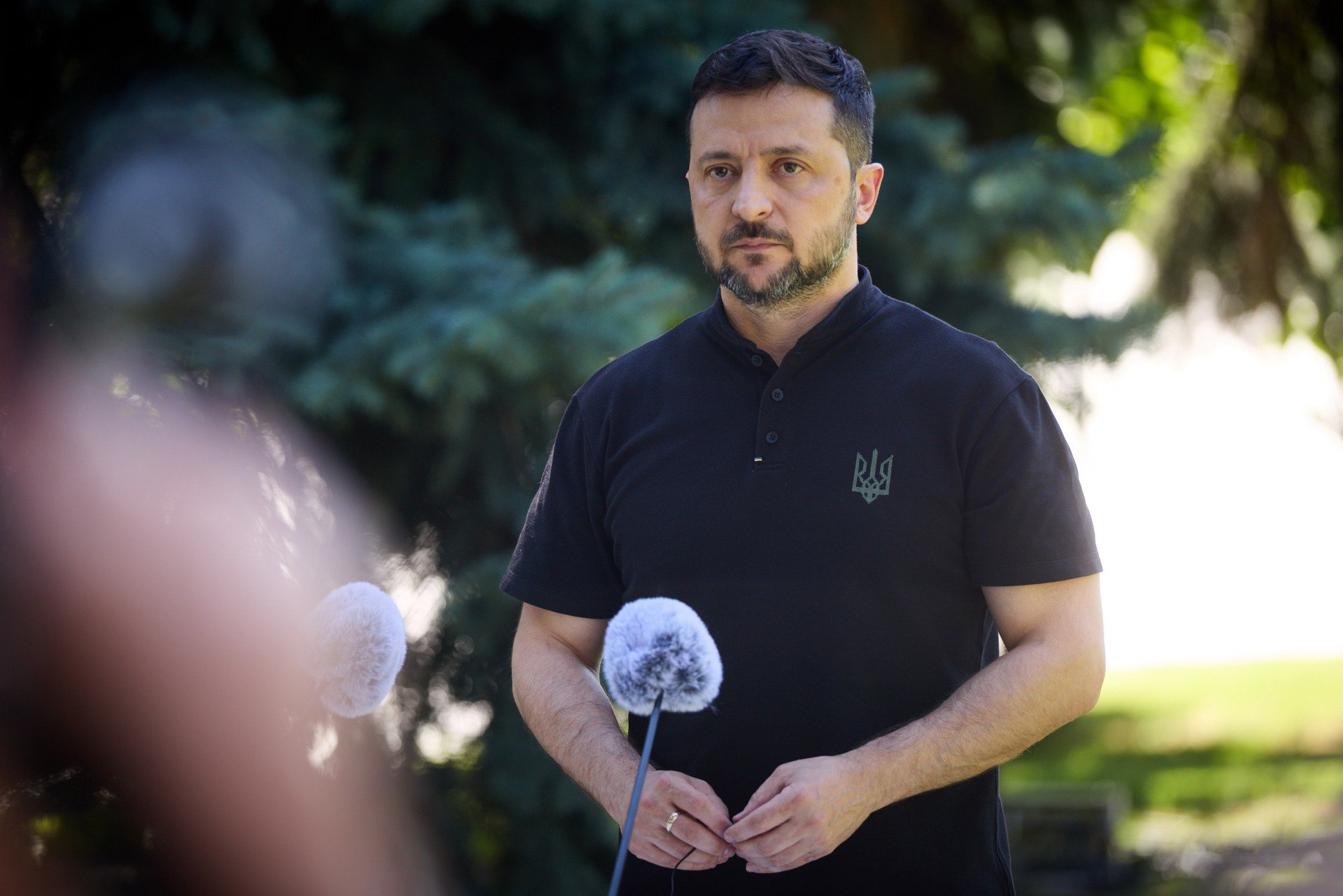Ukrainian President Volodymyr Zelenskyy speaking at microphones during an outdoor press briefing.