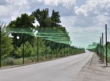 Netting tunnel over a road in Zaporizhzhia, protecting civilians and vehicles from FPV drone attacks.