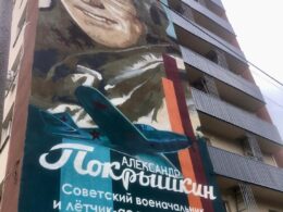 The Russian text reads: "Alexander Pokryshkin - Soviet military commander and pilot-ace during the Great Patriotic War, marshal of aviation." This mural exemplifies the systematic replacement of Ukrainian cultural symbols with Russian military glorification that occupation authorities have implemented throughout Mariupol.