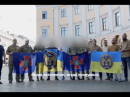 Four Ukrainian soldiers hold National Guard and naval flags following their evacuation by special forces from a hospital on Russian-occupied territory where they had been hiding since 2022. Their faces are blurred for security reasons.