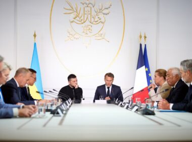 Ukrainian President Volodymyr Zelenskyy sits at a conference table with French President Emmanuel Macron and other European leaders during a Coalition of the Willing meeting.