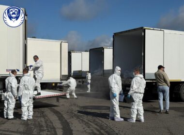 Trucks loaded with bodies of Ukrainian soldiers, accompanied by people in protective gear.